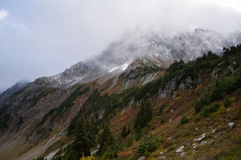 Fog rolling over a rocky ridge above autumn slopes in Washington
